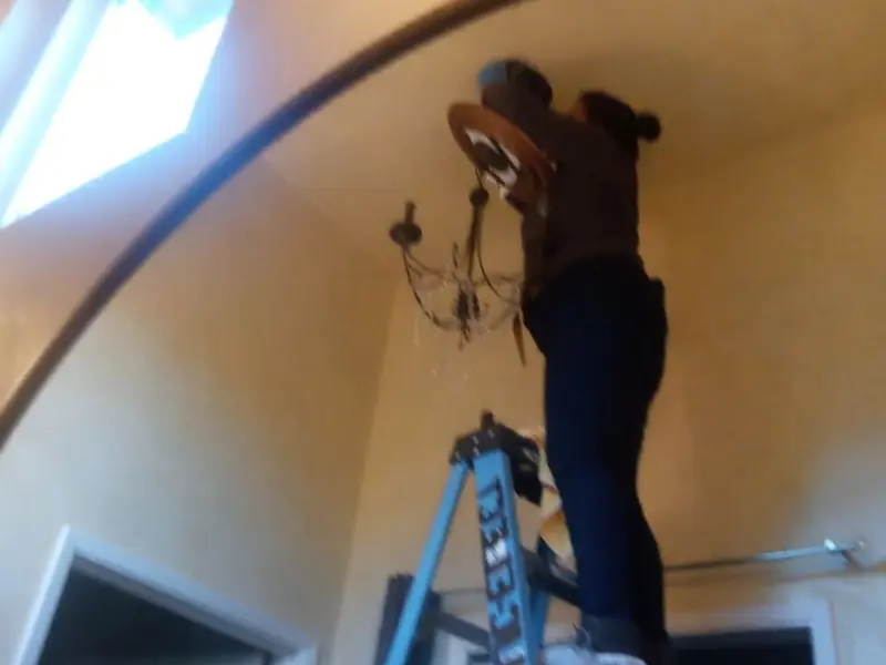 Electrician installing a chandelier in a Holden residence